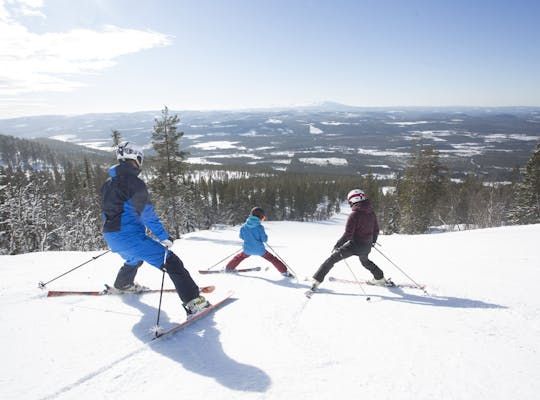 Billedet viser tre personer, der står på ski ned ad en bakke.