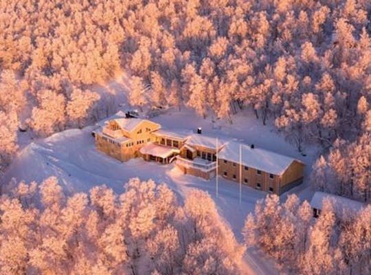 Billedet viser et hotelanlæg set fra oven i et smukt fjeldlandskab.