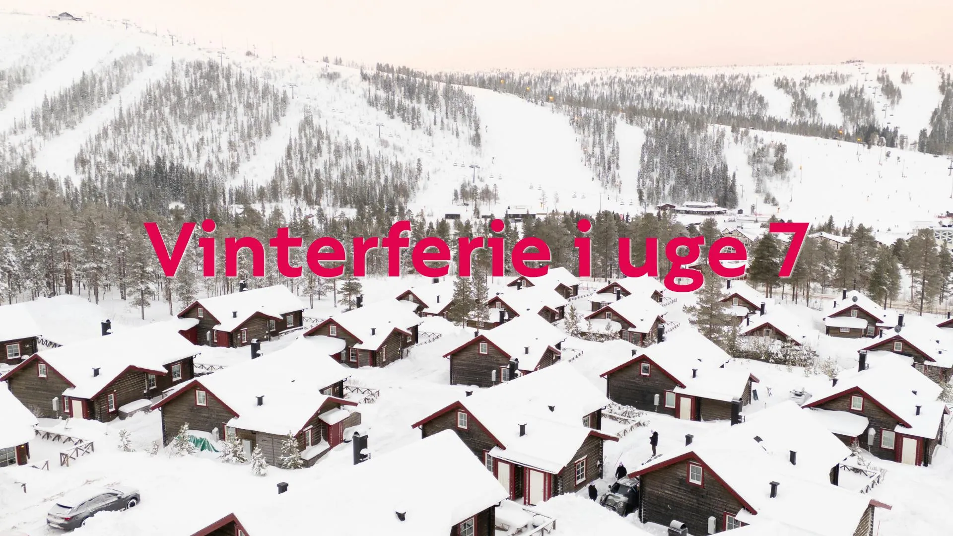 Vinterlandskab med hyggelige hytter og sneklædte skibakker i baggrunden.